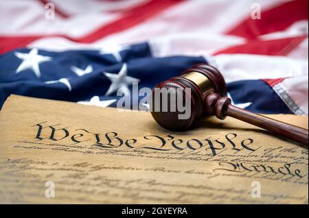Die amerikanische Flagge umhüllte den Gavel-Block eines Richters und die Verfassung der Vereinigten Staaten, um sie als Symbol für Gesetze, Freiheit und Trennung der Regierung zu verwenden Stockfoto