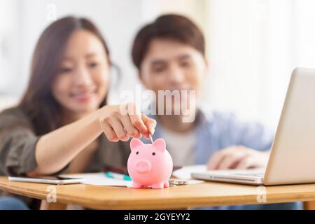Glückliches Paar Münze in Sparschwein einfügen.Familienfinanzierung.Fokus auf Sparschwein. Stockfoto