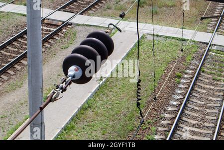 Eine oberirdische Stromleitungskomponente der Eisenbahn entlang einer Strecke mit einem Elektrifizierungssystem der Schiene, das einen elektrischen Zug mit Strom versorgt. Oberleitungskabel Stockfoto