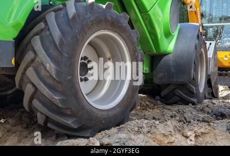 Zwei kleine Bagger auf einer großen Baustelle. Leuchtend grün auf Rädern und gelb auf Schienen. Erdarbeiten und Bau. Schaufelbagger. Mini lo Stockfoto