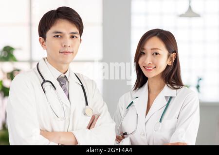 Die Ärzte blicken auf die Kamera und lächeln, während sie mit gekreuzten Armen stehen. Stockfoto