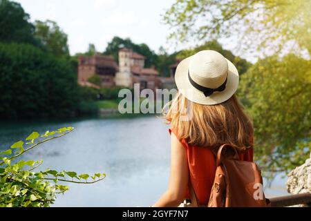 Reisenden Mädchen mit Rucksack Entdeckung versteckte Burg im Park. Junge Frau entspannt sich und fühlt sich glücklich im Park zwischen Vegetation und Fluss. Stockfoto