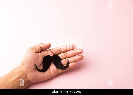 Der Mann verwendet Hand hält schwarzen Schnurrbart, Studio erschossen isoliert auf weißem Hintergrund, Prostatakrebs Bewusstsein Monat, Vatertag, minimale November mou Stockfoto