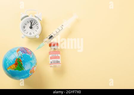 Impffläschchen Flaschen, Spritzen zur Impfung gegen Coronavirus und Globus, Medizinerkrankung, COVID-19-Impfstoff isoliert auf gelbem Backgroun Stockfoto