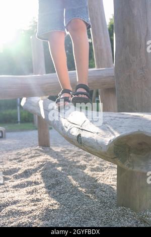 Das Kind geht auf einem Holzbalken auf einem Spielplatz in einem öffentlichen Park. Stockfoto