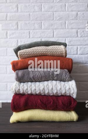 Kuschelige Pullover in Herbstfarben auf braunem Holzhintergrund. Platz für Text. Stockfoto