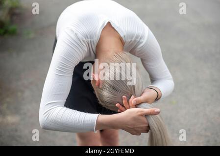 Junge blonde Frau, die Zopf macht Stockfoto