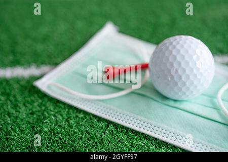 Golfball mit T-Shirt auf Gesichtsmaske zum Schutz des Covid-19-Coronavirus beim Turnier auf dem Golfplatz. Stockfoto