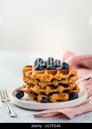 Einfache gesunde glutenfreie Haferwaffeln mit Kopierplatz. Stapel von appetitlichen hausgemachten Waffeln mit Hafermehl dekoriert Heidelbeeren, auf dem Teller über Licht g Stockfoto