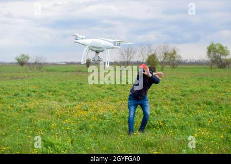 Ein Mann verbirgt sich von einer Kollision mit einer Drohne. Quadrocopter fliegt die Person. Stockfoto