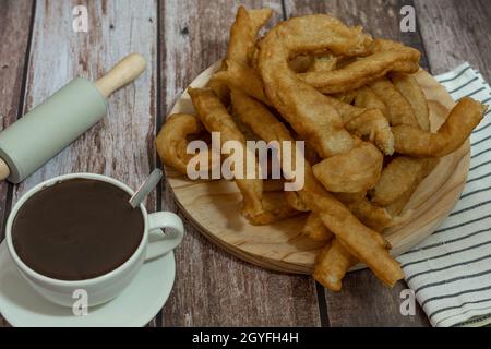 tasse heiße Schokolade mit frisch zubereiteten Churros auf Holzhintergrund typisch spanisches Frühstück an Feiertagen Stockfoto