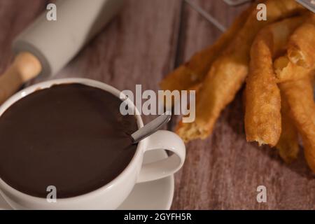 tasse heiße Schokolade mit frisch zubereiteten Churros auf Holzhintergrund typisch spanisches Frühstück an Feiertagen Stockfoto