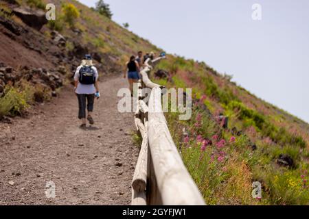 Touristen, die an einem heißen Tag auf dem Wanderweg zum Vesuv, dem Vesuv, wandern. Der Pfad besteht aus scharfem vulkanischem Tuff Stockfoto