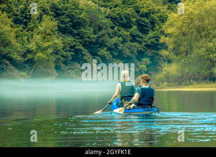Der Mann und die Frau im Kajak im Nebel am Bergsee Stockfoto