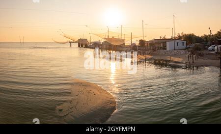 Landschaftsaufnahme von Fischerhütten am Fluss bei Sonnenaufgang mit typischer italienischer Fischmaschine, genannt 'trabucco', Lido di Dante, fiumi uniti Ravenna in der Nähe von Com Stockfoto