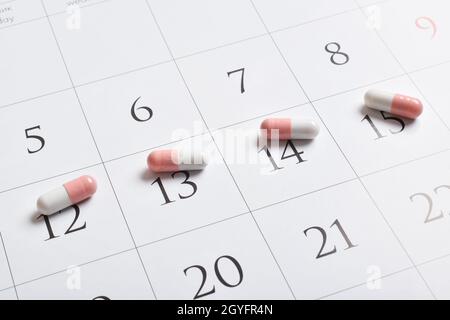 Medikamente. Rosa pharmazeutische Kapseln mit Tabletten stehen im Kalender. Ein Konzept für einen Medikamentenplan, einen Zeitplan, eine Liste oder einen Kalender. Stockfoto