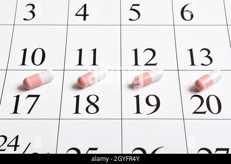 Medikamente. Rosa pharmazeutische Kapseln mit Tabletten stehen im Kalender. Ein Konzept für einen Medikamentenplan, einen Zeitplan, eine Liste oder einen Kalender. Stockfoto
