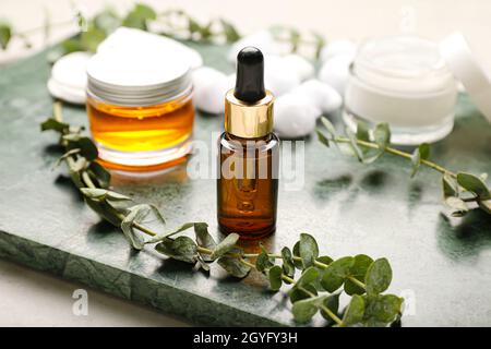 Brett mit Kosmetikprodukten und Eukalyptuszweigen, Nahaufnahme Stockfoto