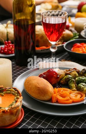 Teller mit leckerem Thanksgiving-Dinner und einem Glas Wein auf einem festlich servierten Tisch Stockfoto