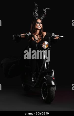 Frau für Halloween mit Motorrad auf dunklem Hintergrund gekleidet Stockfoto