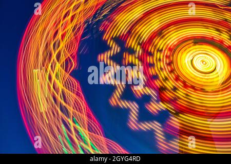 Lebhafte Sonnenuntergangsfarben auf einem Karneval am Riesenrad oder bei einer fairen Fahrt in der Nacht Stockfoto
