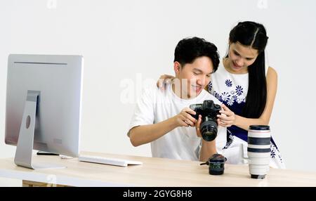 Der asiatische Fotograf erlaubt dem Model, die auf dem Kamerabildschirm aufgenommenen Bilder anzusehen. Das junge Model ist sehr zufrieden mit ihrem Foto. Die Atmosphäre im ph-wert Stockfoto