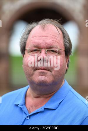 Lorsch, Deutschland. September 2021. Hermann Schefers, Direktor des Welterbes Kloster Lorsch, steht vor dem sogenannten Torsaal oder Königssaal mit seiner weltberühmten bunten Sandsteinfassade façade, dem einzigen erhaltenen Gebäude des Klosters Lorsch aus der karolingischen Zeit. Der prächtige Torsaal ist eines der berühmtesten Beispiele frühmittelalterlicher Architektur. Seit 30 Jahren gehört die Stätte zum UNESCO-Weltkulturerbe. (To dpa '30 Jahre UNESCO-Welterbe Kloster Lorsch - viele Fragen offen') Quelle: Arne Dedert/dpa/Alamy Live News Stockfoto