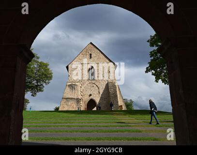Lorsch, Deutschland. September 2021. Das Kirchenfragment einer Basilika aus dem frühen 12. Jahrhundert ist durch einen Torbogen des sogenannten Torsaals oder Königshauses, dem einzigen erhaltenen Gebäude aus der karolingischen Zeit im Kloster Lorsch, zu sehen. Der prächtige Torsaal ist eines der berühmtesten Beispiele frühmittelalterlicher Architektur. Seit 30 Jahren gehört die Stätte zum UNESCO-Weltkulturerbe. (To dpa '30 Jahre UNESCO-Welterbe Kloster Lorsch - viele Fragen offen') Quelle: Arne Dedert/dpa/Alamy Live News Stockfoto