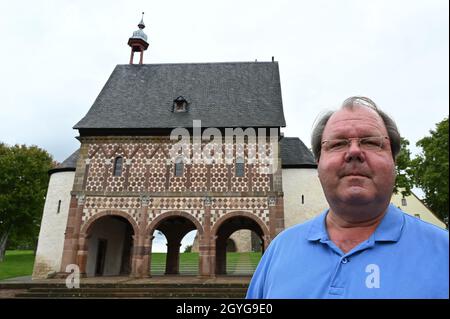 Lorsch, Deutschland. September 2021. Hermann Schefers, Direktor des Welterbes Kloster Lorsch, steht vor dem sogenannten Torsaal oder Königssaal mit seiner weltberühmten bunten Sandsteinfassade façade, dem einzigen erhaltenen Gebäude des Klosters Lorsch aus der karolingischen Zeit. Der prächtige Torsaal ist eines der berühmtesten Beispiele frühmittelalterlicher Architektur. Seit 30 Jahren gehört die Stätte zum UNESCO-Weltkulturerbe. (To dpa '30 Jahre UNESCO-Welterbe Kloster Lorsch - viele Fragen offen') Quelle: Arne Dedert/dpa/Alamy Live News Stockfoto