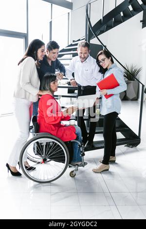 Gruppe von lateinischen Geschäftsleuten, die auf der Treppe mit Transgender-Frau auf dem Rollstuhl in Latina Amerika sitzen Stockfoto