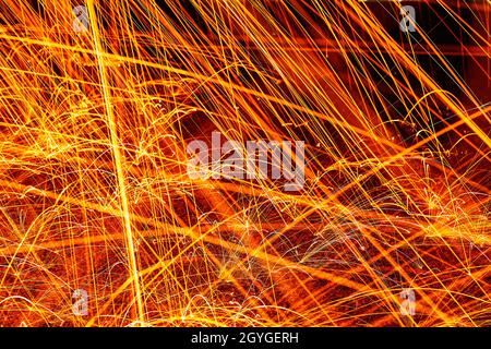 In der Nacht funken orange und gelb gegen einen Gehsteig Stockfoto