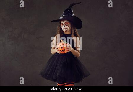 Studio-Porträt des kleinen Mädchens in schwarzem Kleid und Hexenhut für Halloween gekleidet Stockfoto