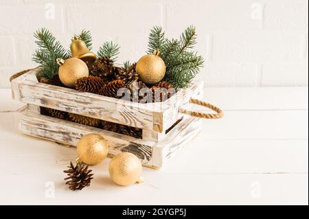 Dekorative Box aus Holz mit eigenen Händen mit Neujahrskugeln und Zapfen Fichte auf einem Holztisch Stockfoto
