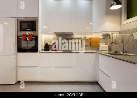 Stilvolles Interieur der modernen Küche mit Marmortisch und Haushaltsgeräten. Stockfoto