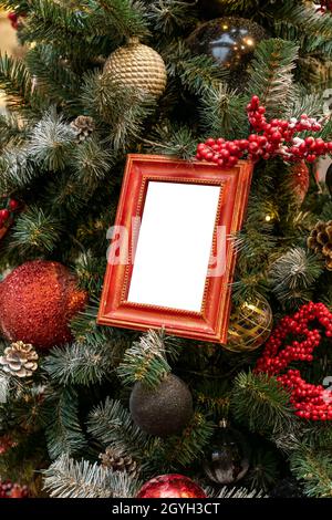 Nahaufnahme von weihnachtsbaum mit Kugeln aus roten, silbernen Farben und leeren Fotorahmen mockup geschmückt. Festliches Konzept der Winter-Grußkarte. Stockfoto