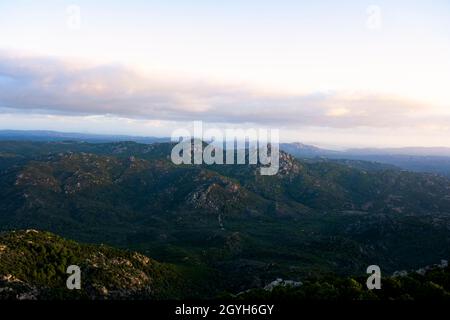 Blick von oben, atemberaubende Landschaft mit einer Bergkette und einem Tal bei einem wunderschönen Sonnenaufgang. Panoramablick von Vedetta Monte Pino, Sardinien. Stockfoto