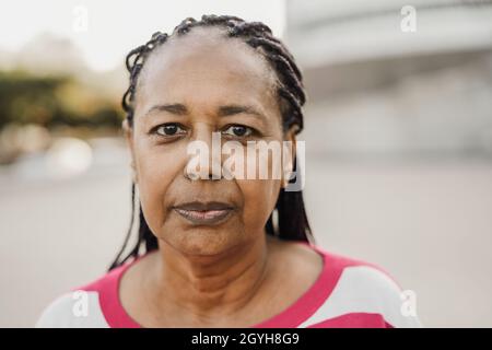 Ältere afrikanische Frau, die in der Stadt die Kamera im Freien betrachtet – Fokus auf Gesicht Stockfoto