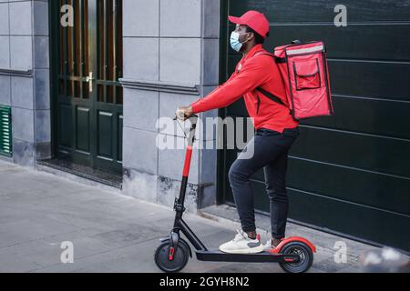 African Rider Delivering Meal with Electric Scooter - Fokus auf Gesicht Stockfoto