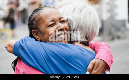 Hochrangige Frauen aus verschiedenen Rassen treffen sich und umarmen sich im Freien Stockfoto