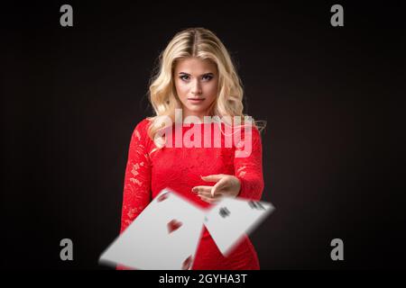 Junge schöne emotionale Frau wirft Karten auf einem schwarzen Hintergrund im Studio. Poker Stockfoto