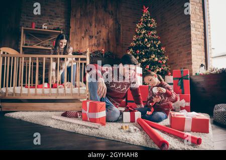 Foto von Familie bindenden Menschen sitzen Boden vorbereiten noel Geschenke tragen Pullover in dekorierten Weihnachten zu Hause drinnen Stockfoto