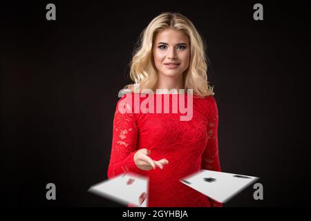 Junge schöne emotionale Frau wirft Karten auf einem schwarzen Hintergrund im Studio. Poker Stockfoto