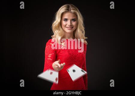 Junge schöne emotionale Frau wirft Karten auf einem schwarzen Hintergrund im Studio. Poker Stockfoto