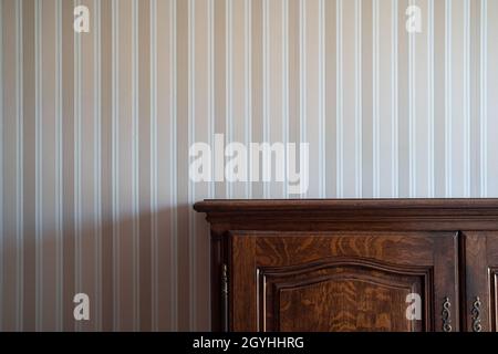 Vorderansicht Nahaufnahme eines leeren braunen Holzschranks mit Vintage-Schubladen an einer weißen Wand mit beigefarbenen Streifen Stockfoto