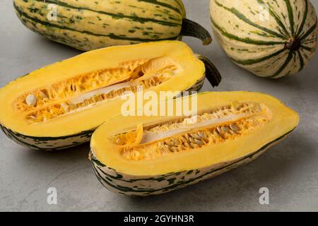 Gestreifte ganze Delicata-Pumkins und halbierte mit Samen aus nächster Nähe Stockfoto