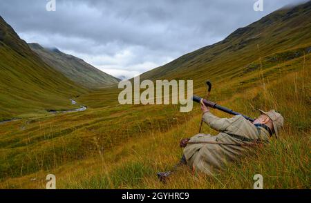 Ross-Shire, Scottish Highlands, Großbritannien. Oktober 2021. Nachdem die Red Stag-Saison in wenigen Tagen zu Ende geht, beginnt Rob Dhu A Ghillie in den schottischen Highlands, um Red Deer an einem nebligen nassen Morgen auf einem abgelegenen Hügel in Ross-Shire mit dem traditionellen Spionageglas oder -Teleskop zu suchen. Quelle: Matt Limb OBE/Alamy Live News Stockfoto