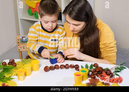 Mutter und Sohn Formen herbstliche Raupe aus Kastanien und Plastilin Stockfoto