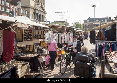 Ein Mann schiebt sein Fahrrad durch den Waterlooplein Markt, Waterloopleinmarkt, in Amsterdam, Niederlande. Stockfoto