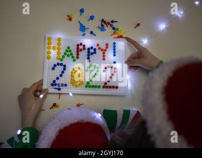 Die Zahlen des neuen Jahres 2022 sind mit plastikfarbenem Mosaik ausgekleidet. Von Kindern in weihnachtsmützen gemacht. Ideen für die Kreativität mit Kindern, die Entwicklung von Flosse Stockfoto