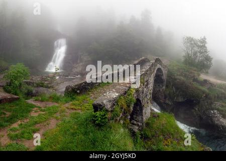 Aufgenommen an einem späten Frühlingsabend, unter dichtem Nebel und leichtem Regen. Dies ist die Steinbrücke, die den Ribordone-Bach im Val Chiusella überspannt, Stockfoto